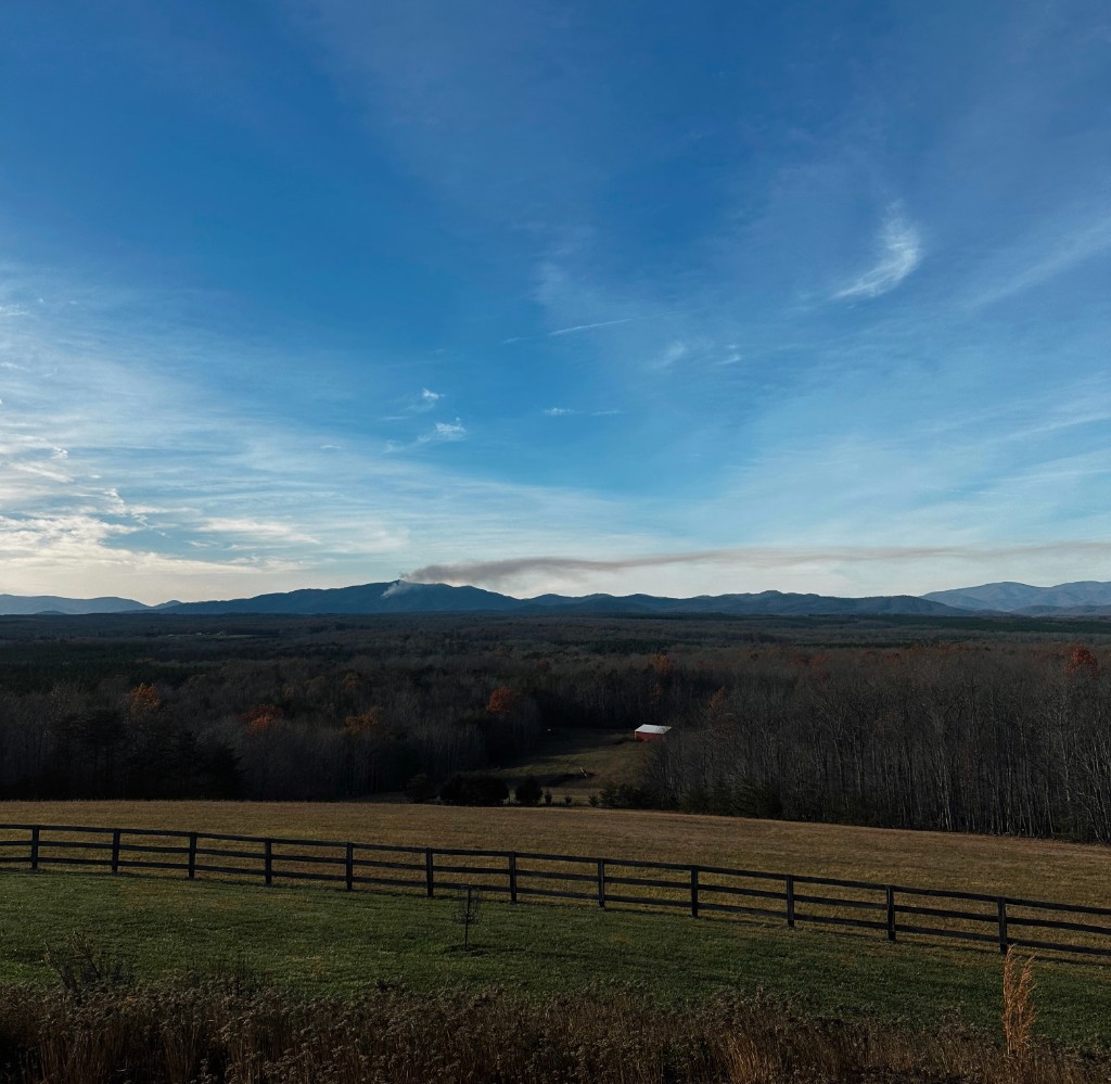 Pasture and post-and-rail fence with distant mountain ridgeline
