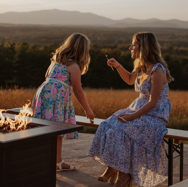 Mother and daughter by the fire pit at sunset