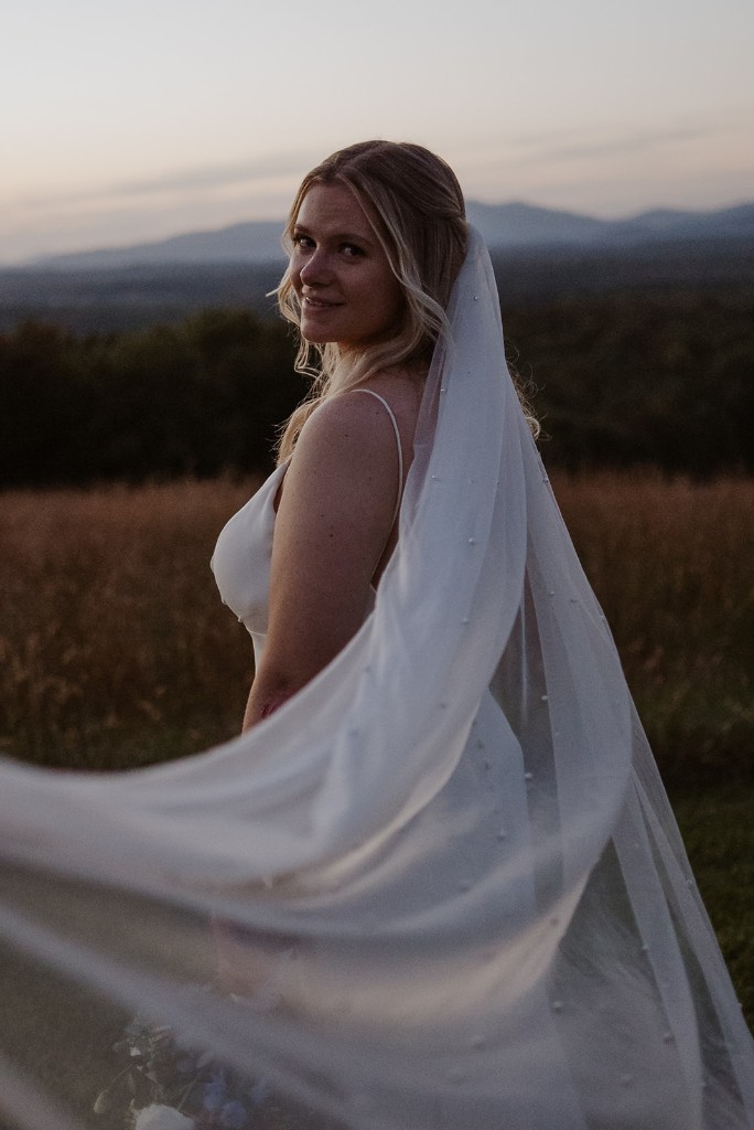 Bride with veil in the meadow at sunset